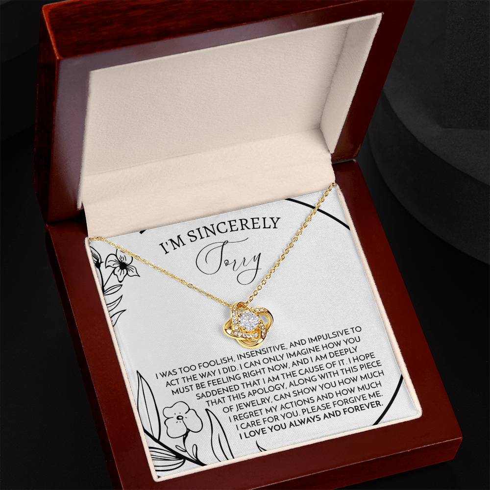 The Sorry-Care For You - Love Knot Necklace features a pendant with intertwined loops adorned with sparkling cubic zirconia crystals. It is elegantly displayed on a card that conveys an apology message, reading "I'm sincerely sorry," expressing deep regret and love.