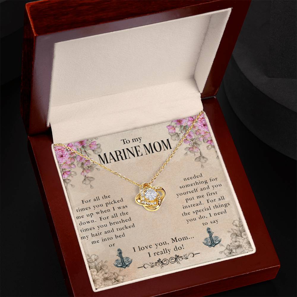 A gold-tone To My Marine Mom, For All The Times You Picked Me Up - Love Knot Necklace with cubic zirconia crystals on the heart-shaped pendant, presented in an open jewelry box, with a printed message to a "marine mom" expressing love and appreciation by ShineOn Fulfillment.