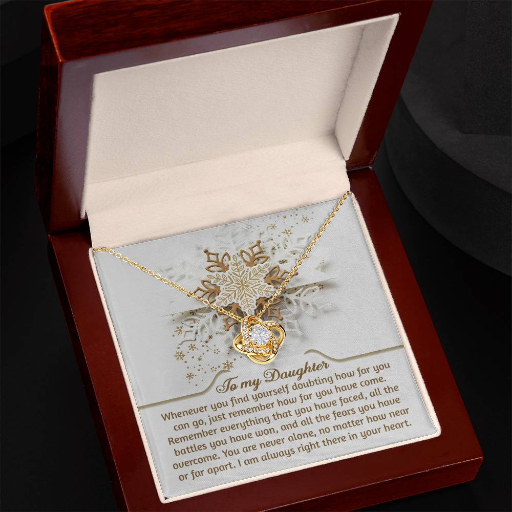 Displayed in an open jewelry box, the Daughter-You Can Go - Love Knot Necklace showcases a heart pendant embellished with cubic zirconia crystals. The inscription on the interior lid reads "To my Daughter," symbolizing the unbreakable bond between you.