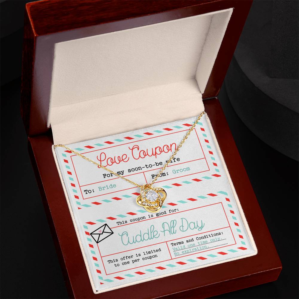 The "To Wife, Wedding-Love Coupon - Love Knot Necklace" adorned with cubic zirconia crystals sits atop a decorated card labeled "Love Coupon." The card, addressed to "Bride" from "Groom," offers a "Cuddle All Day" coupon with no expiration date—a perfect gift for a loved one.