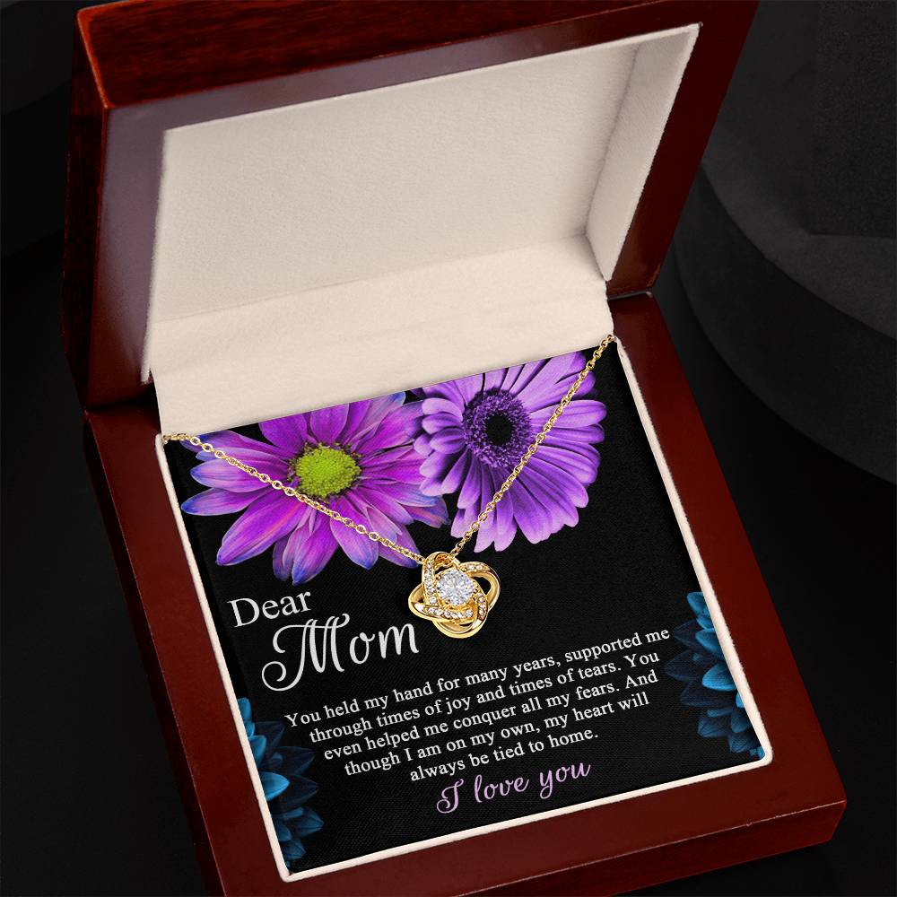 The "To Mom, Held My Hand - Love Knot Necklace" is a beautiful gold heart-shaped pendant with a diamond, presented in an elegant box. It features a heartfelt message: "Dear Mom, You held my hand for many years... I'm always so tied to you. I love you." This personalized gift perfectly expresses your enduring affection.