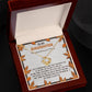 Open box showcasing a Daughter-My Greatest Blessing - Love Knot Necklace, featuring an interlocking heart pendant adorned with cubic zirconia crystals, symbolizing the unbreakable bond. The message inside the box lid reads "To My Daughter" and is surrounded by autumn leaf decorations.