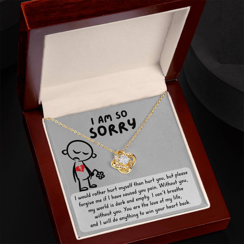 An open jewelry box reveals a gold necklace with a heart-shaped pendant and a note stating "I am so sorry." The heartfelt apology is further personalized by the Sorry-Dark And Empty - Love Knot Necklace, making it an exquisite symbol of remorse.