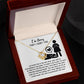 The Sorry-Stop Talking - Love Knot Necklace, embellished with cubic zirconia crystals, is elegantly presented in a wooden box. The box features a heartfelt message saying "I'm Sorry That I Hurt You," alongside an illustration of a woman and a heart symbol.