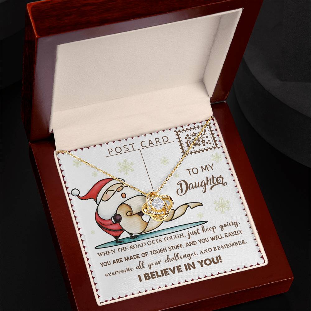 The Daughter-Keep Going - Love Knot Necklace, featuring sparkling cubic zirconia, is presented in a gift box accompanied by a card with a Santa illustration that reads "To My Daughter." It includes an inspiring message about overcoming challenges and honors the enduring bond between you.