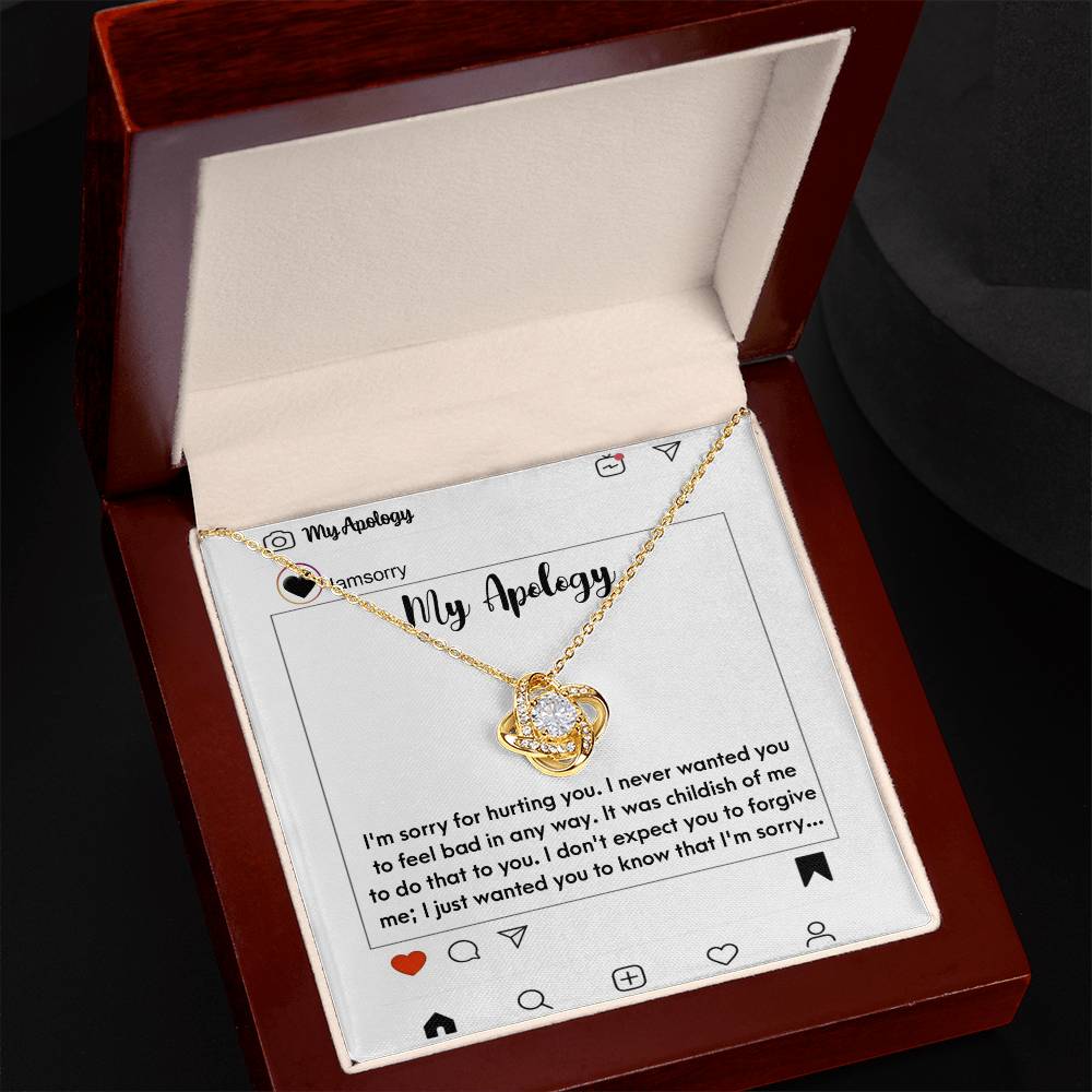 The "Sorry-My Apology - Love Knot Necklace," featuring a white gold finish and sparkling cubic zirconia crystals, is elegantly displayed in a box. The background includes an emotional apology message presented as a simulated social media post.