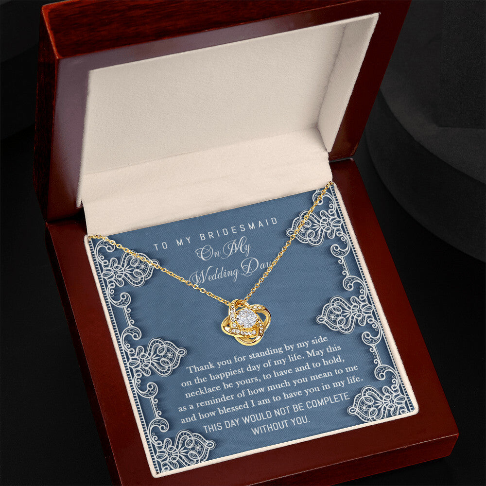 To Bridesmaid, By My Side - Love Knot Necklace with interlocking heart design, adorned with sparkling cubic zirconia crystals, displayed in a box with a heartfelt message for the bridesmaid. The message expresses gratitude for her unwavering support on the wedding day.