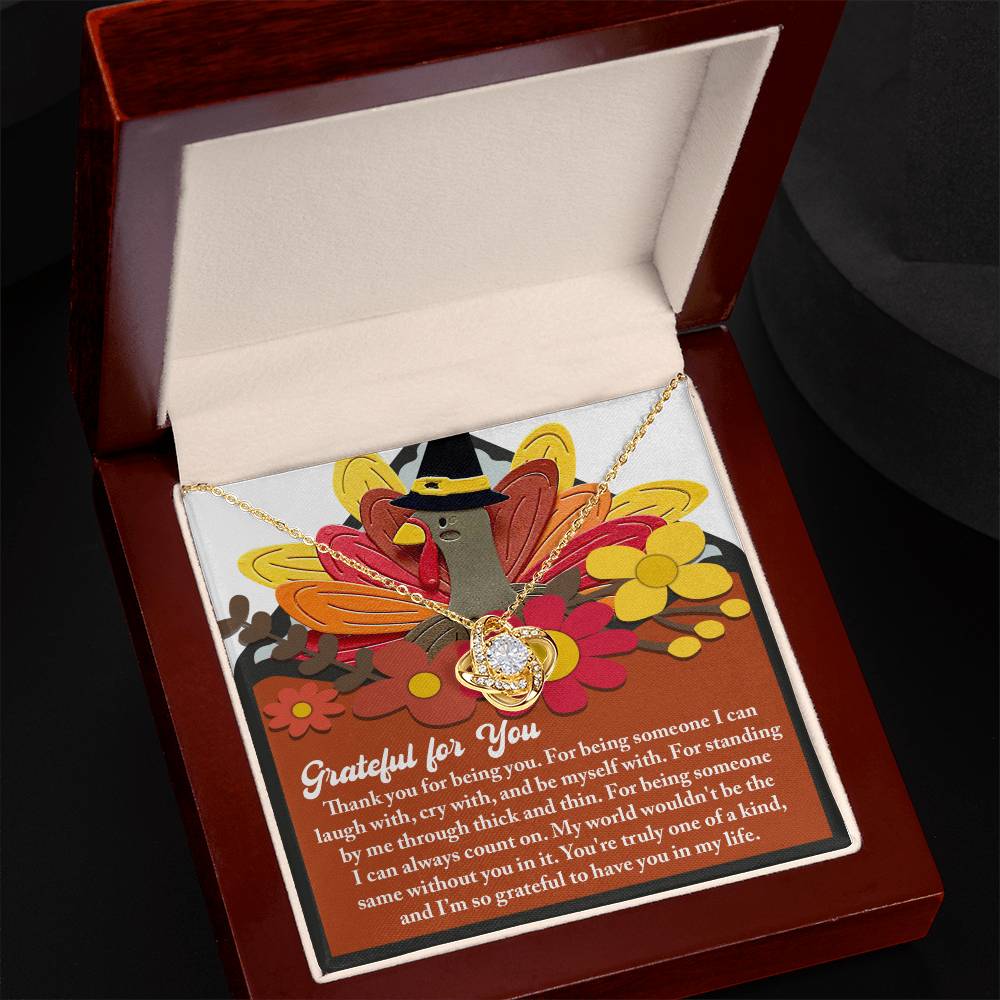 The Thanksgiving-Being You - Love Knot Necklace featuring shimmering cubic zirconia crystals rests in a jewelry box on top of a Thanksgiving-themed card decorated with a turkey and flowers, accompanied by a heartfelt note of gratitude.