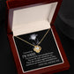 A silver Sorry-Painful Lesson - Love Knot Necklace on a dark background, adorned with shimmering cubic zirconia crystals. The text includes an apology, a statement of love, and an affirmation of unity.