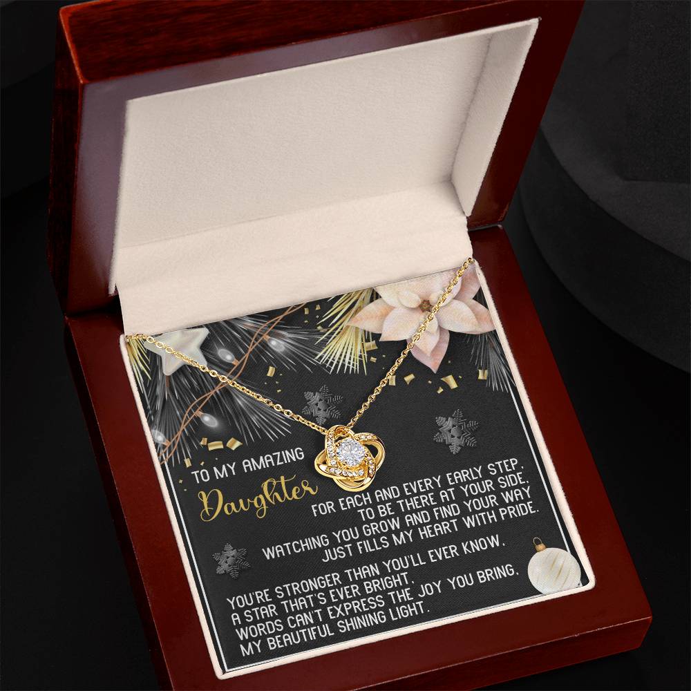 The Daughter-Shining Light - Love Knot Necklace, featuring a heart pendant, is beautifully showcased in a box. Within the lid, a meaningful message graces an ornate card, creating an ideal personalized gift. The necklace is adorned with cubic zirconia crystals that enhance its charm and sparkle.