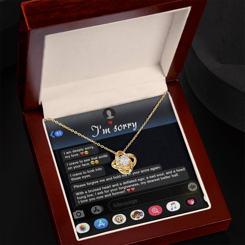 An "I'm sorry" message is displayed on a phone screen along with the stunning Sorry, Rebuild Our Connection - Love Knot Necklace. This necklace, available in either white gold or yellow gold finish and adorned with cubic zirconia crystals, perfectly complements the heartfelt plea for forgiveness.