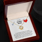 An open jewelry box displaying a To My Nurse Mom, To The World You're Just A Nurse - Love Knot Necklace with an adjustable chain length and a pendant shaped like a heart adorned with cubic zirconia crystals, accompanied by a heartfelt message acknowledging the contributions and love of ShineOn Fulfillment.