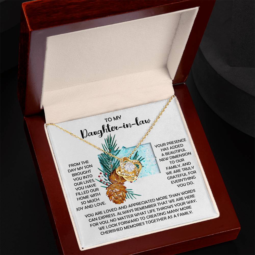 The Daughter-in-Law-Here For You - Love Knot Necklace is a personalized gift adorned with interlocking hearts and sparkling cubic zirconia crystals. It comes in a wooden box with a heartfelt message expressing gratitude and love for a cherished daughter-in-law.