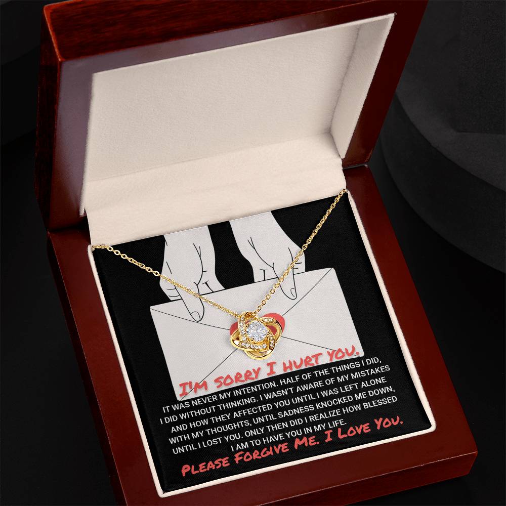 A Sorry-Without Thinking - Love Knot Necklace with a white gold finish and diamond pendant rests in an open jewelry box. Inside the lid is an apology letter printed in red and white text, enhancing the heartfelt presentation.