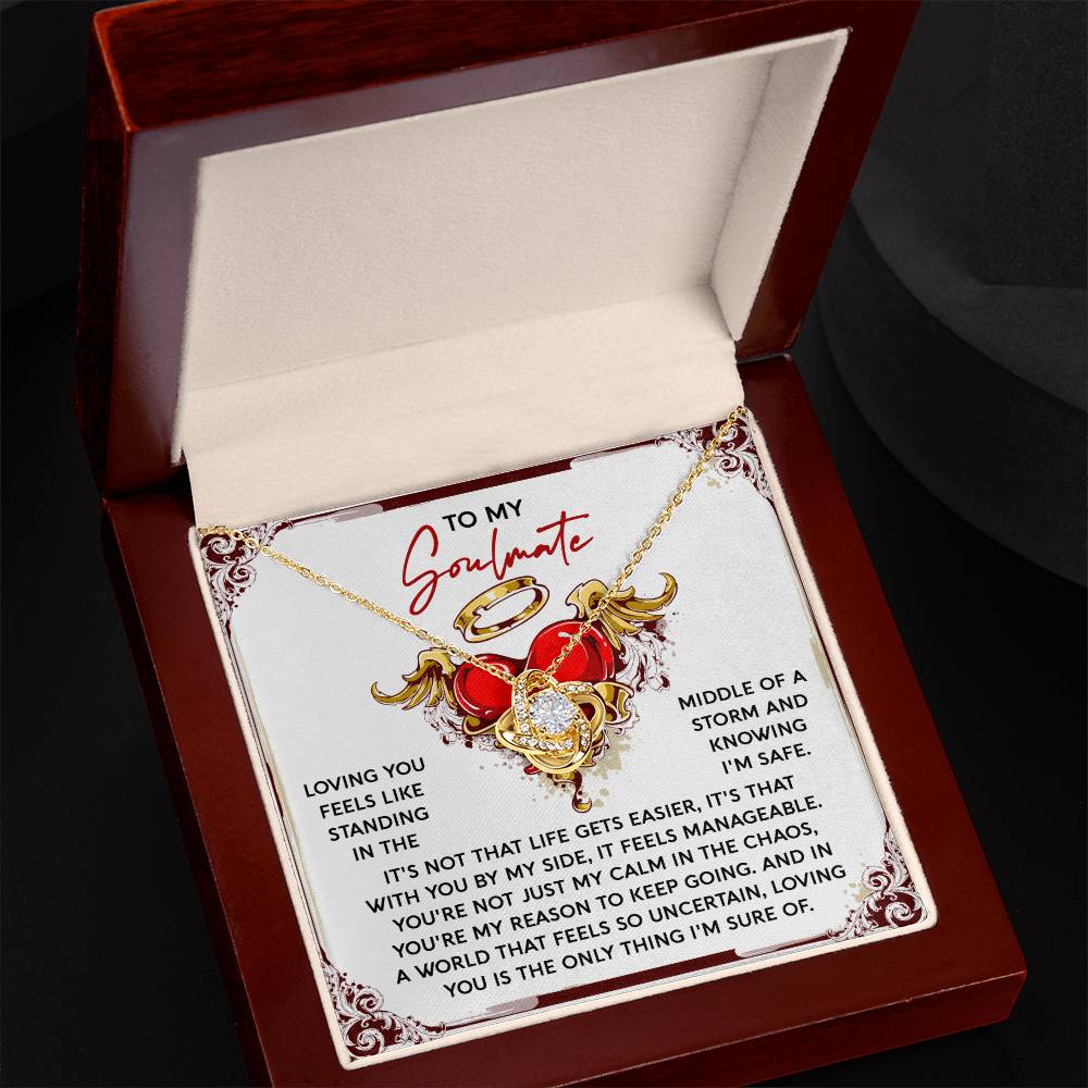 A personalized gift, the gold Soulmate-Keep Going Love Knot Necklace features intertwined hearts and a rose nestled in an open jewelry box, accompanied by a card that romantically addresses "To My Soulmate.