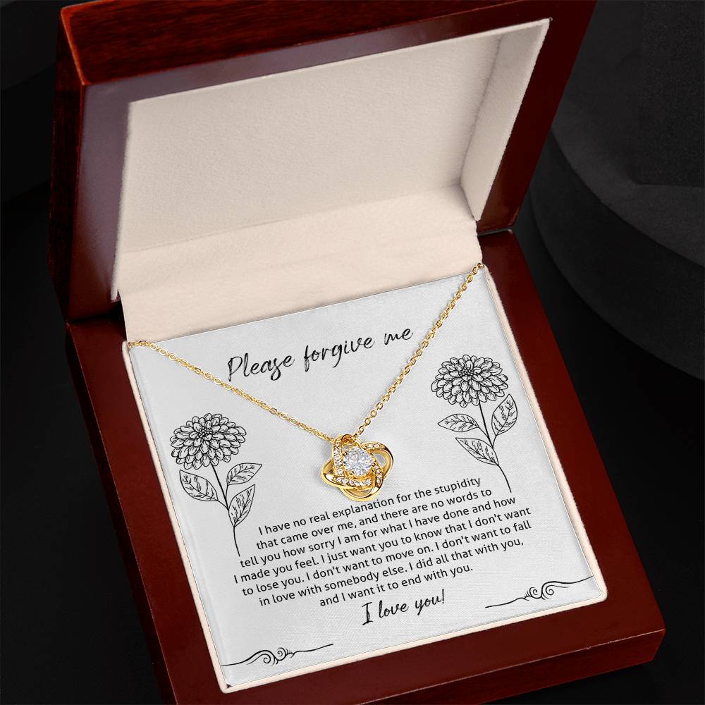 The Sorry-Real Explanation - Love Knot Necklace features an intertwined heart pendant adorned with cubic zirconia crystals, presented in a box. The box lid includes an apology note with floral illustrations, expressing regret, love, and a plea for forgiveness.