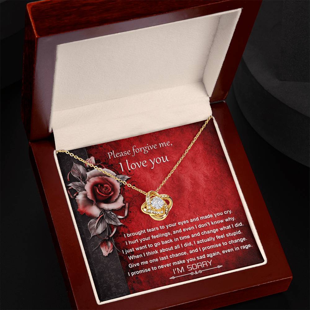 A "Sorry-One Last Chance - Love Knot Necklace" gleams in an open jewelry box, adorned with premium cubic zirconia crystals. Accompanying it is a heartfelt apology message printed in the background, symbolizing an unbreakable bond.