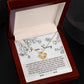 A Sorry-Your Big Heart - Love Knot Necklace with intertwined heart pendants rests in an open, cushioned box. The inside lid of the box features a printed apology message with floral illustrations and "I am Sorry" at the top, making it a heartfelt personalized gift adorned with premium cubic zirconia crystals.