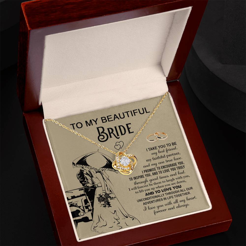 A "To My Bride, Faithful Partner - Love Knot Necklace" adorned with cubic zirconia crystals is displayed in a box. The background features a silhouette of a couple under an umbrella, two rings, and a heartfelt message to a bride, making it the perfect unique gift.