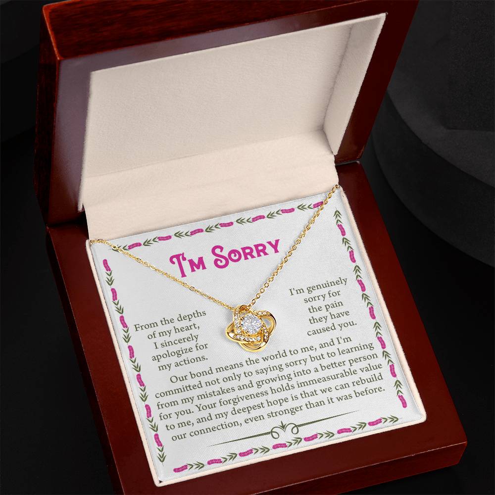 The Sorry-A Better Person - Love Knot Necklace features a heart pendant and arrives in a jewelry box. Crafted from 14k white gold and adorned with cubic zirconia crystals, the necklace shines brightly. The box also contains a printed apology message with "I'm Sorry" in large text.