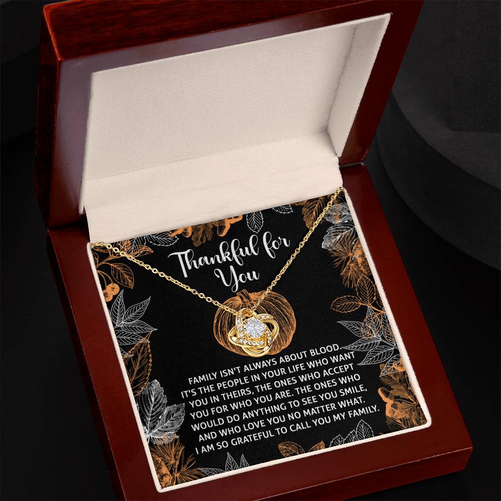 A Thanksgiving-To Call You Love Knot Necklace featuring a heart pendant, presented in a gift box. The white gold finish shines brilliantly like cubic zirconia, and the box includes text expressing gratitude for supportive loved ones, regardless of blood relation.