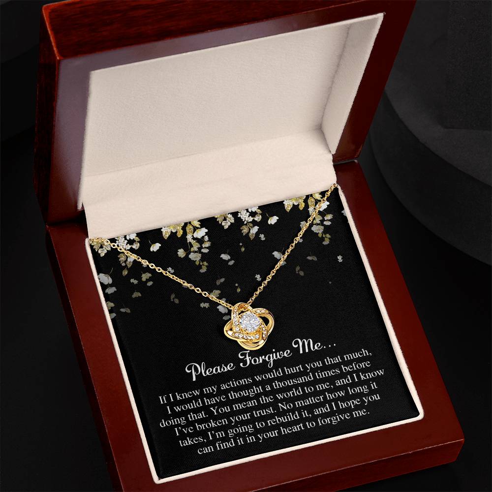 The "Sorry-Broken Your Trust - Love Knot Necklace," adorned with cubic zirconia crystals, is elegantly displayed in an open, dark-colored jewelry box. Inside the lid, a heartfelt apology message enhances the sentiment of the white gold or yellow gold finish.