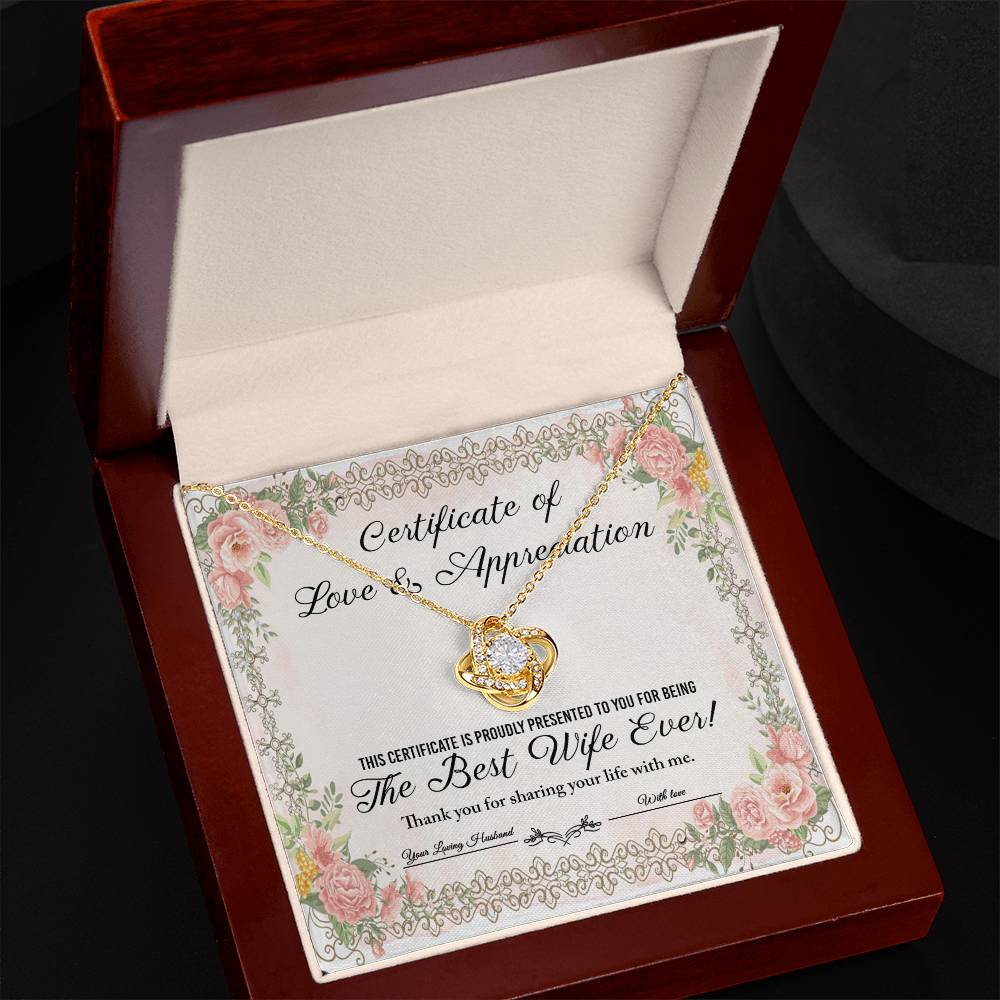 The "To Wife, Love & Appreciation - Love Knot Necklace" features a heart-shaped pendant elegantly displayed over a "Certificate of Love & Appreciation," expressing gratitude for being "The Best Wife Ever!" The necklace showcases a gold finish with sparkling cubic zirconia crystals, and the certificate is beautifully adorned with floral borders.