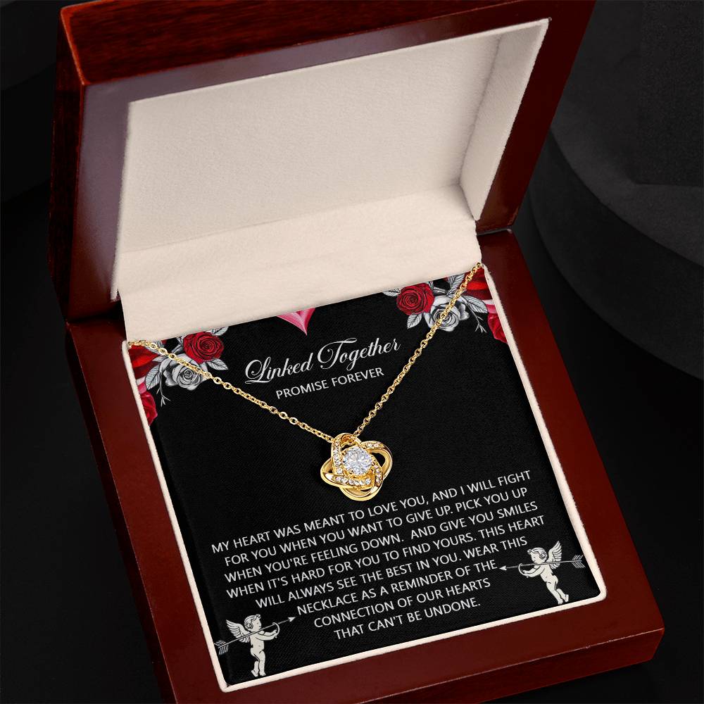 The Soulmate-To Find Yours - Love Knot Necklace, featuring a gold heart-shaped design with a dazzling diamond, sits elegantly in a jewelry box. It comes with a heartfelt note adorned with red rose designs and cherubs, making it the perfect gift for your loved one.