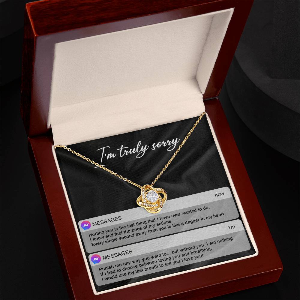 The Sorry-Away From You - Love Knot Necklace features interwoven heart pendants adorned with cubic zirconia crystals, and comes in a box with "I'm truly sorry" inscribed above. Accompanying the necklace are two text message excerpts expressing regret and love, making it an ideal personalized gift.