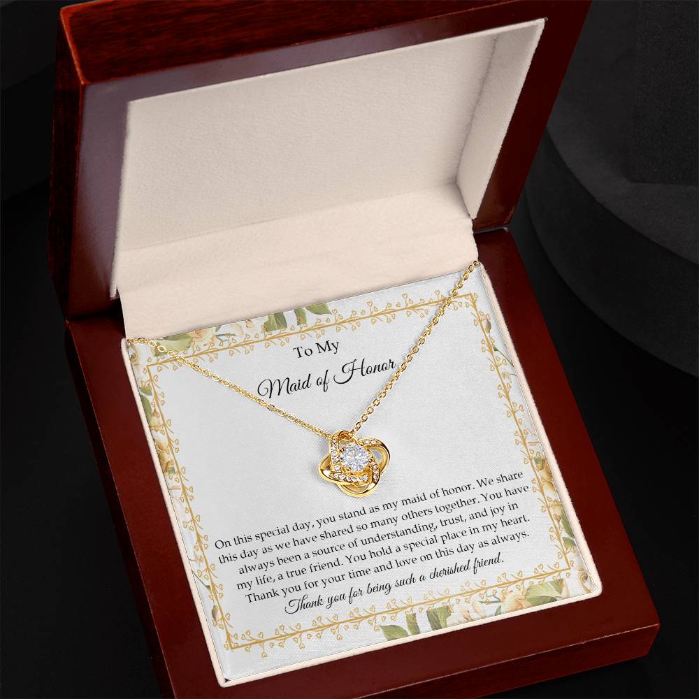 Presenting the "To Maid of Honor, Share This Day - Love Knot Necklace," featuring a stunning pendant adorned with cubic zirconia crystals and finished in white gold. It is beautifully displayed in a box embellished with a floral border and includes a heartfelt message expressing gratitude and appreciation to the "Maid of Honor.