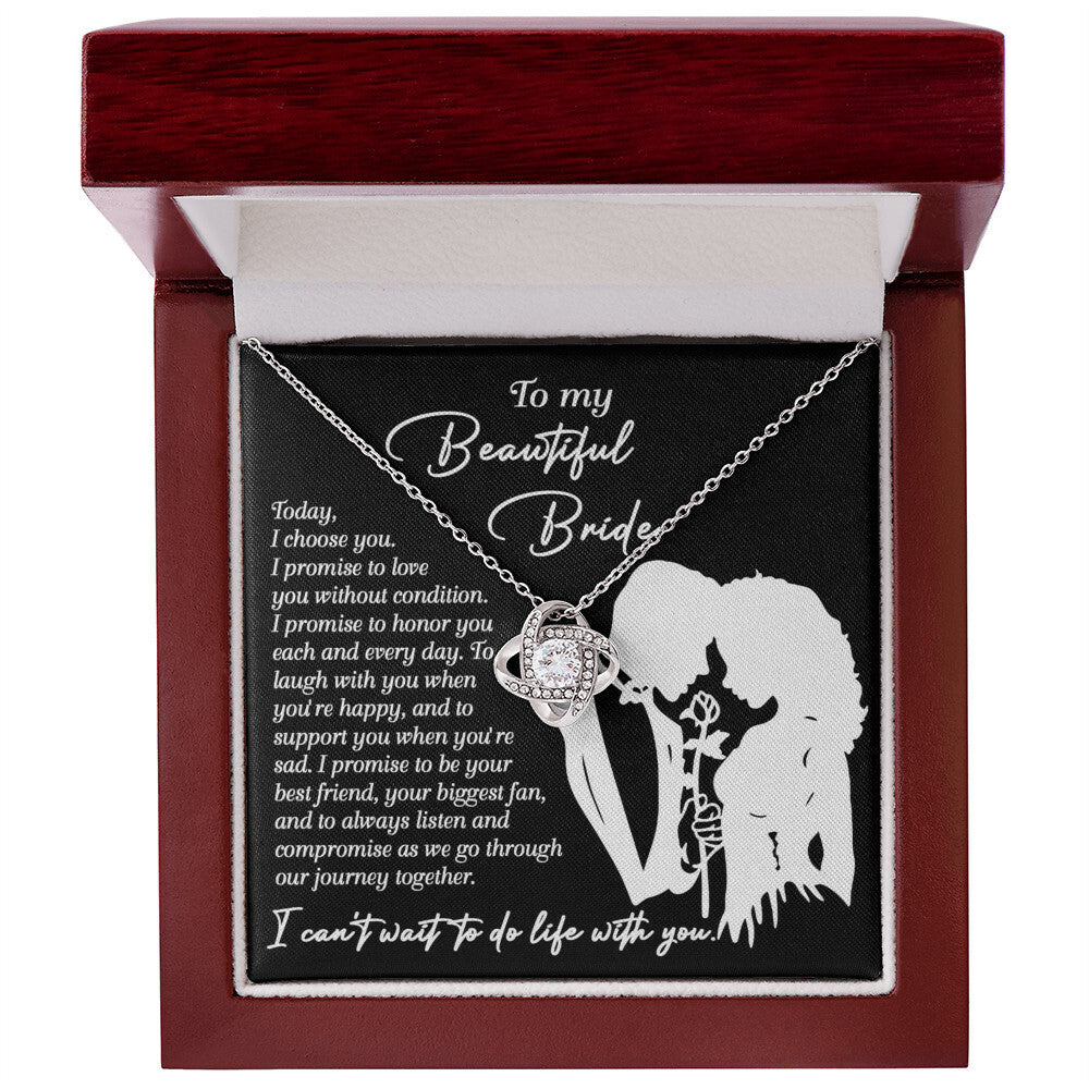 A To My Beautiful Bride, I Choose You - Love Knot Necklace with an intertwined design is displayed in a box. The box has a message to a bride expressing love and promises to honor, laugh, support, and be by her side through their journey together. The necklace features sparkling cubic zirconia crystals, making it a perfect personalized gift.