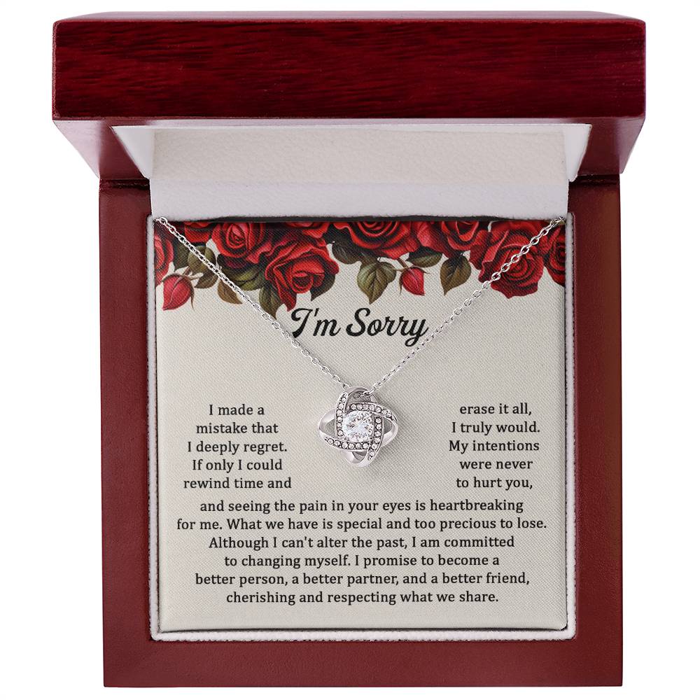 The "Sorry, Precious To Lose - Love Knot Necklace," adorned with cubic zirconia crystals, is displayed on a card featuring an apology message set against a background of red roses. The message expresses regret and a commitment to change.