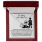 A Sorry-Stop Talking - Love Knot Necklace featuring a heart-shaped pendant adorned with cubic zirconia crystals is displayed in an open jewelry box. The inside lid reads "I'm Sorry THAT I HURT YOU" with an illustration of a person kneeling next to a heart symbol. Text apologizing is visible, making it the perfect personalized gift.