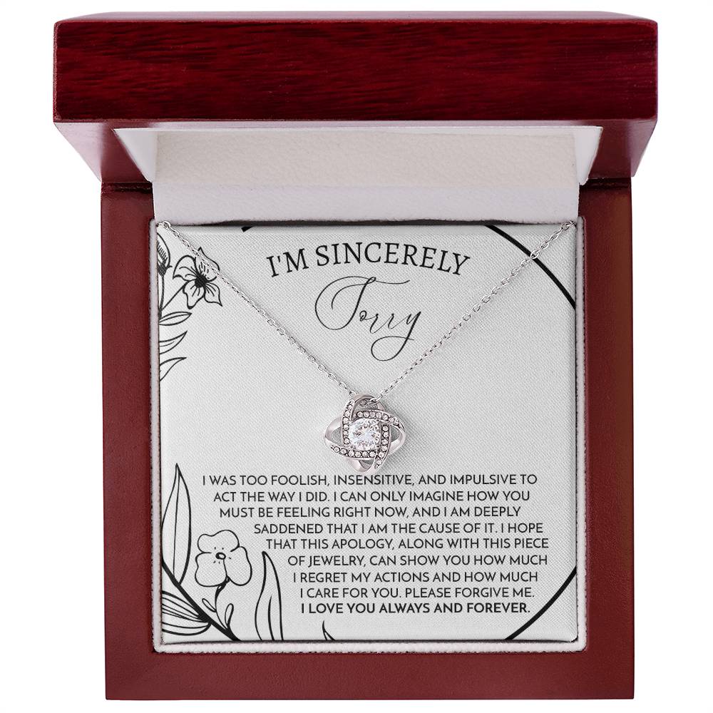 The Sorry-Care For You - Love Knot Necklace features a pendant with intertwined loops adorned with sparkling cubic zirconia crystals. It is elegantly displayed on a card that conveys an apology message, reading "I'm sincerely sorry," expressing deep regret and love.