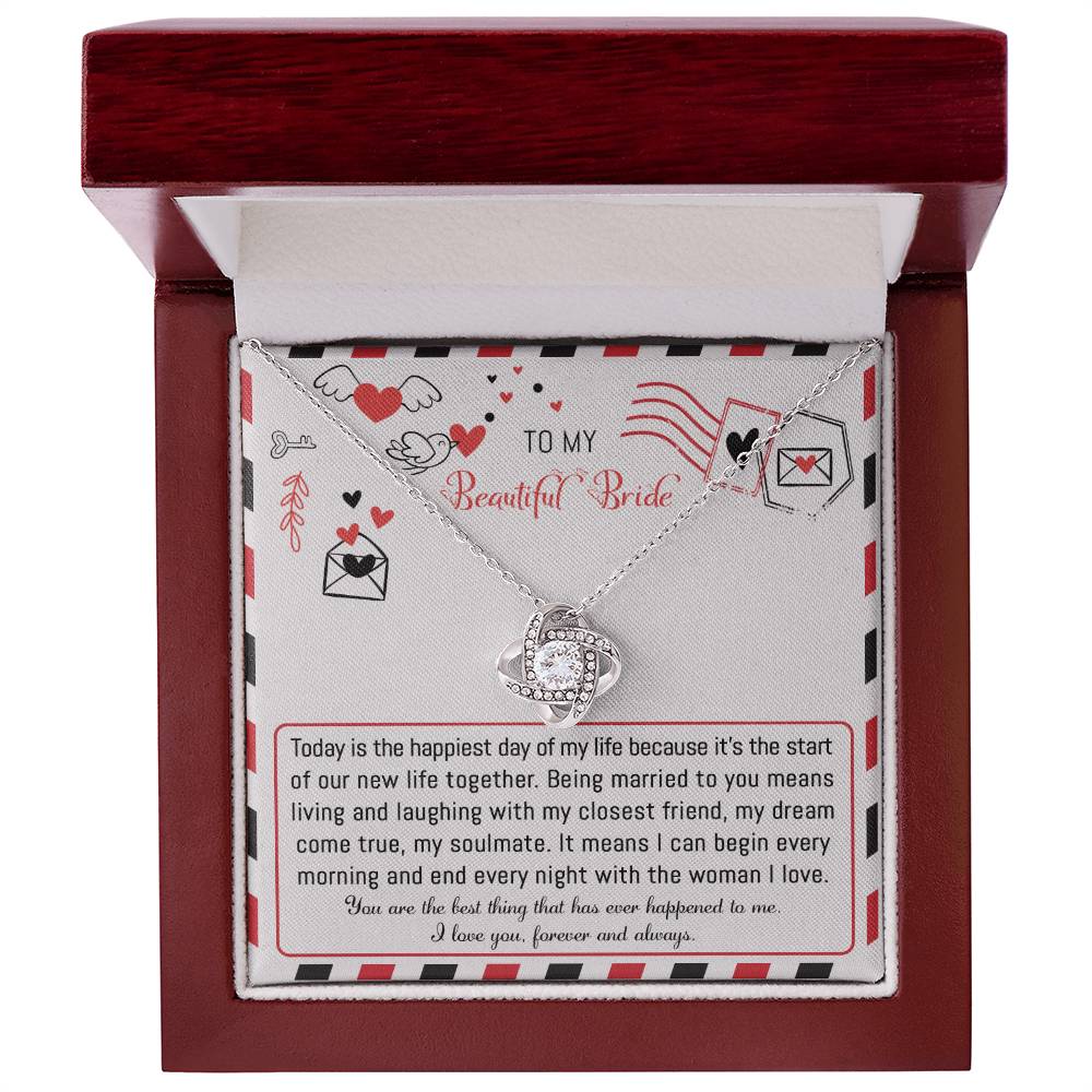 The "To Bride, The Happiest Day - Love Knot Necklace," beautifully crafted from 14k white gold and adorned with cubic zirconia crystals, is elegantly presented in a box featuring a heartfelt message for the bride, expressing love and joy for their life together.