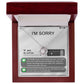 The "Sorry-Breaks My Soul - Love Knot Necklace" is a silver necklace featuring a pendant, beautifully displayed in its packaging. The front of the packaging includes a heartfelt apology message, text messages, a battery icon showing 96% for AirPods, and an illustrated figure. This intricately crafted piece is made from 14k white gold and adorned with cubic zirconia crystals.