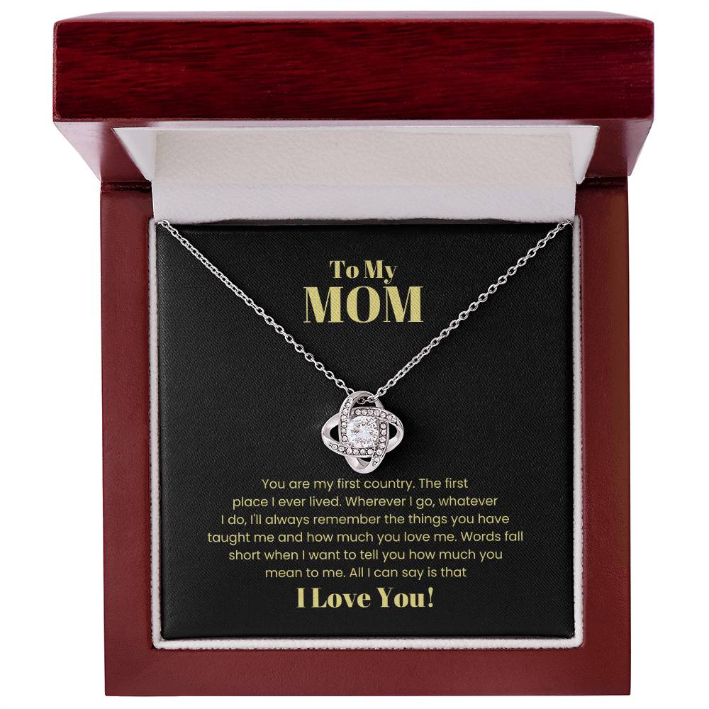 A "To My Mom, You Are My First Country - Love Knot Necklace" in a wooden gift box. The 14k white gold pendant is adorned with cubic zirconia crystals. The inscription reads, "To My MOM. Words fall short when I want to tell you how much you mean to me. All I can say is that I Love You!