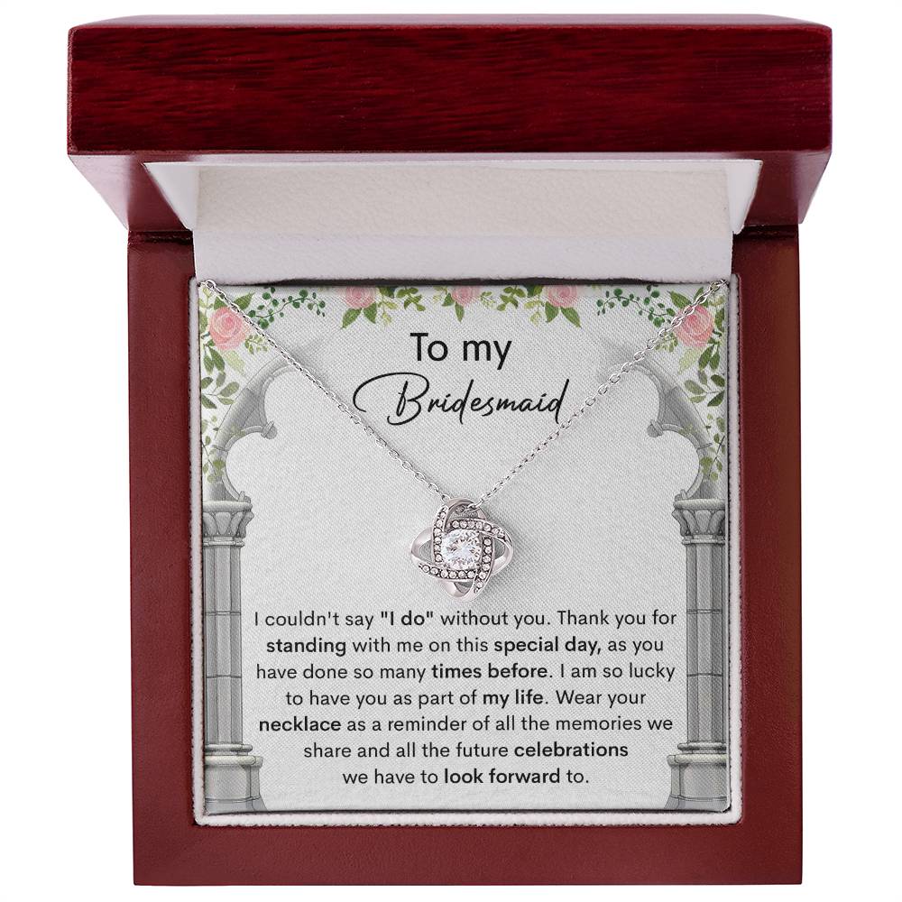 A personalized gift, the *To My Bridesmaid, Standing With Me - Love Knot Necklace* with cubic zirconia crystals, is displayed on a card that expresses gratitude to a bridesmaid, highlighting the importance of her support on the special day.