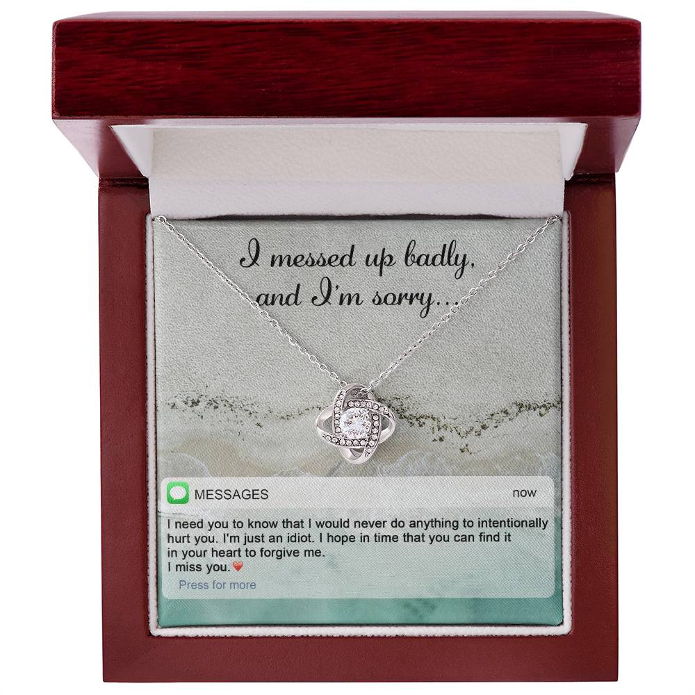 The "Sorry-Just An Idiot - Love Knot Necklace" features a heart-shaped pendant adorned with cubic zirconia crystals, presented on a card inscribed with "I messed up badly, and I'm sorry." It comes complete with a heartfelt text message expressing deep remorse and seeking forgiveness.