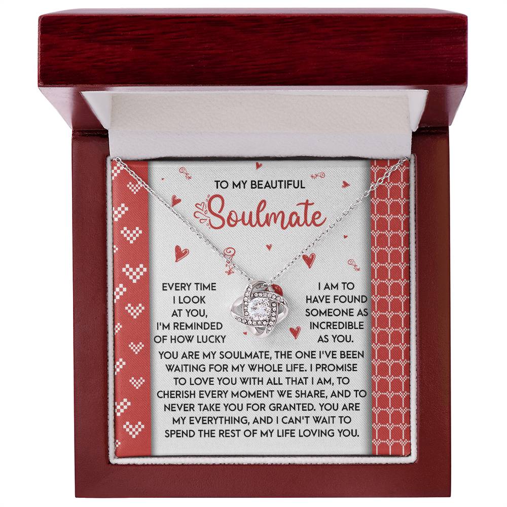 The Soulmate-My Whole Life Love Knot Necklace, with a silver design and gold finish adorned with cubic zirconia, is beautifully presented in a red velvet-lined box. The inner lid contains a heartfelt message to a soulmate, enhancing its sentimental value.