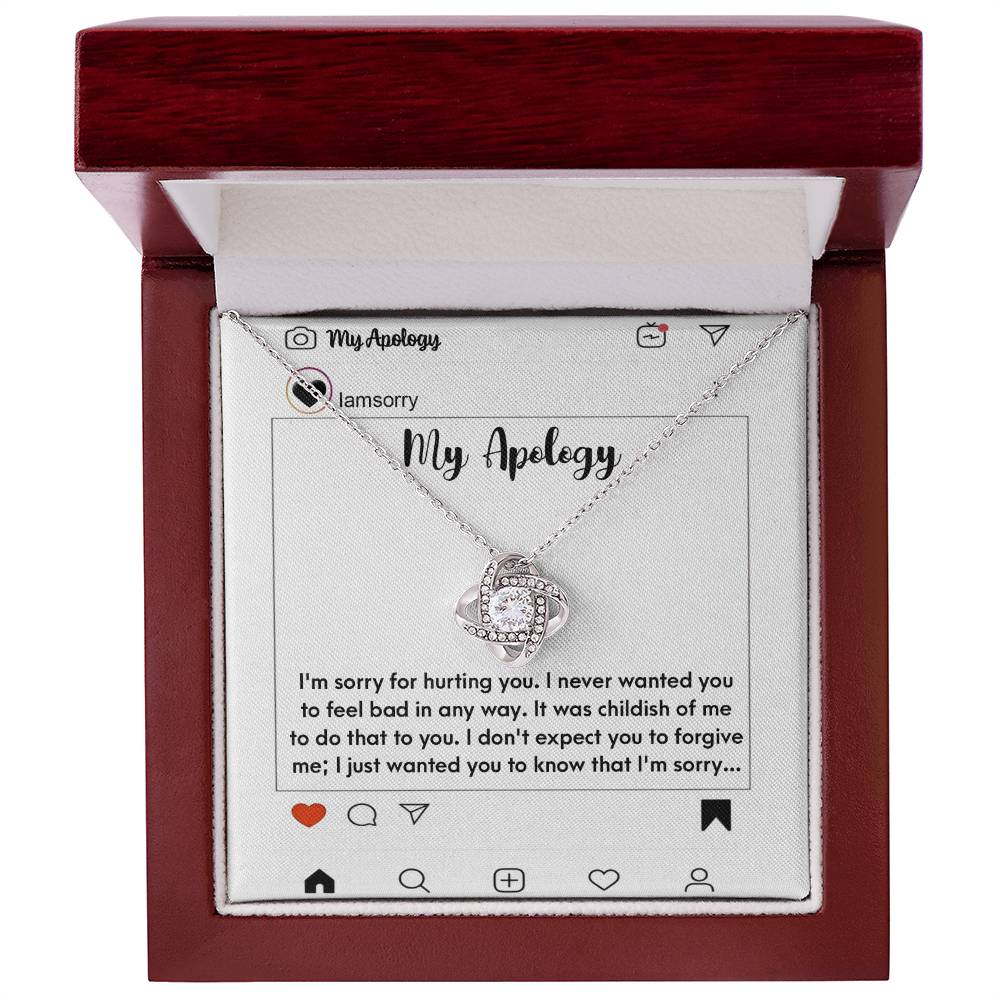 The "Sorry-My Apology - Love Knot Necklace," featuring a white gold finish and sparkling cubic zirconia crystals, is elegantly displayed in a box. The background includes an emotional apology message presented as a simulated social media post.