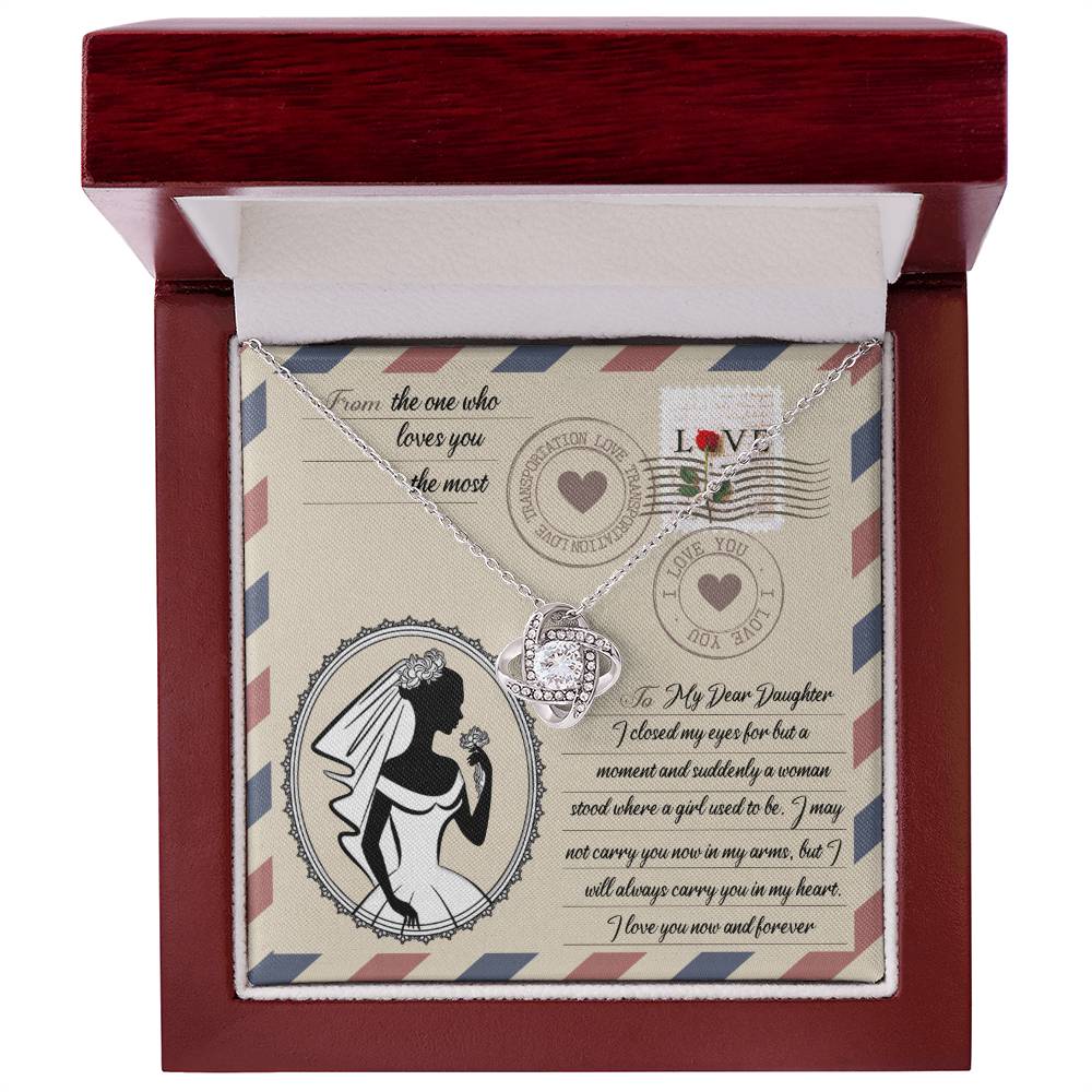 A To Daughter Wedding, In My Arms - Love Knot Necklace with a heart-shaped pendant on a card with a vintage design, featuring cubic zirconia crystals, a silhouette of a woman in a wedding gown, and a heartfelt message addressed to a daughter.