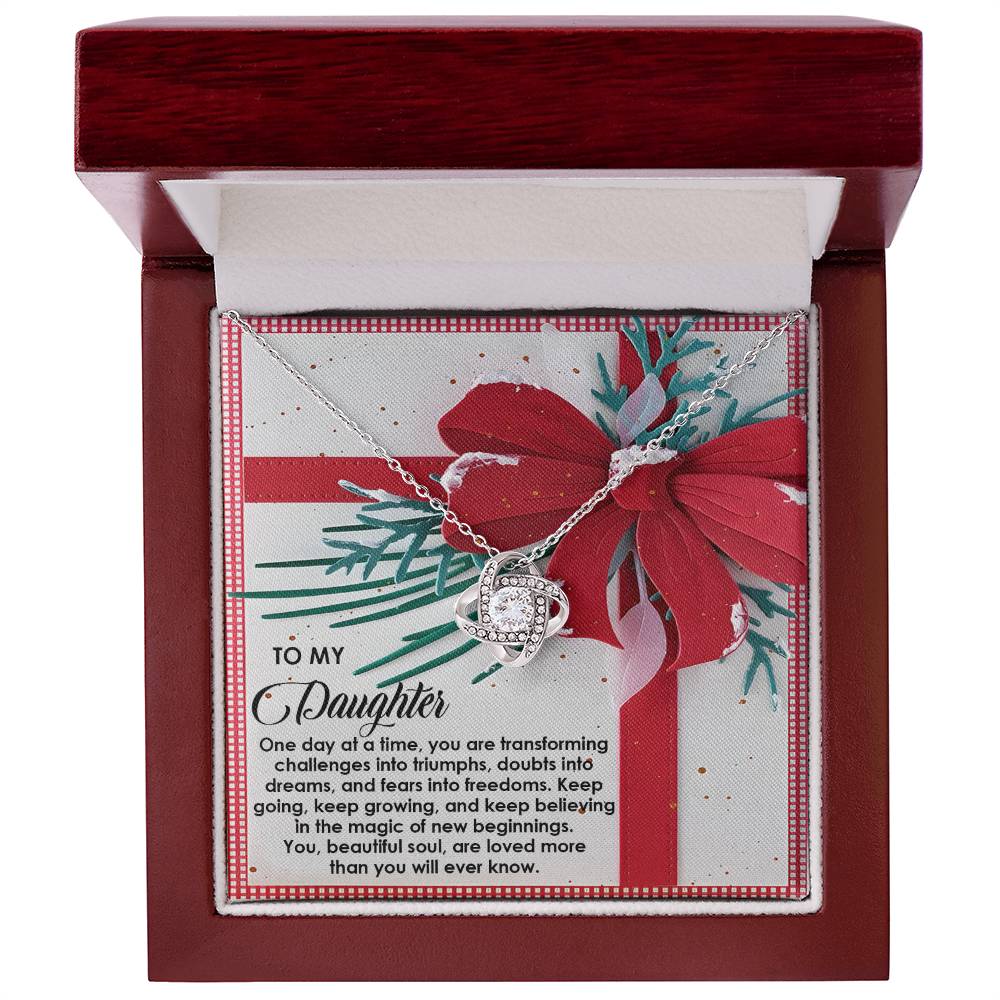 The Daughter-Beautiful Soul - Love Knot Necklace in silver, showcasing a heart design adorned with cubic zirconia, is packaged in a gift box complete with a message card for your daughter. The box is elegantly finished with a red bow design.