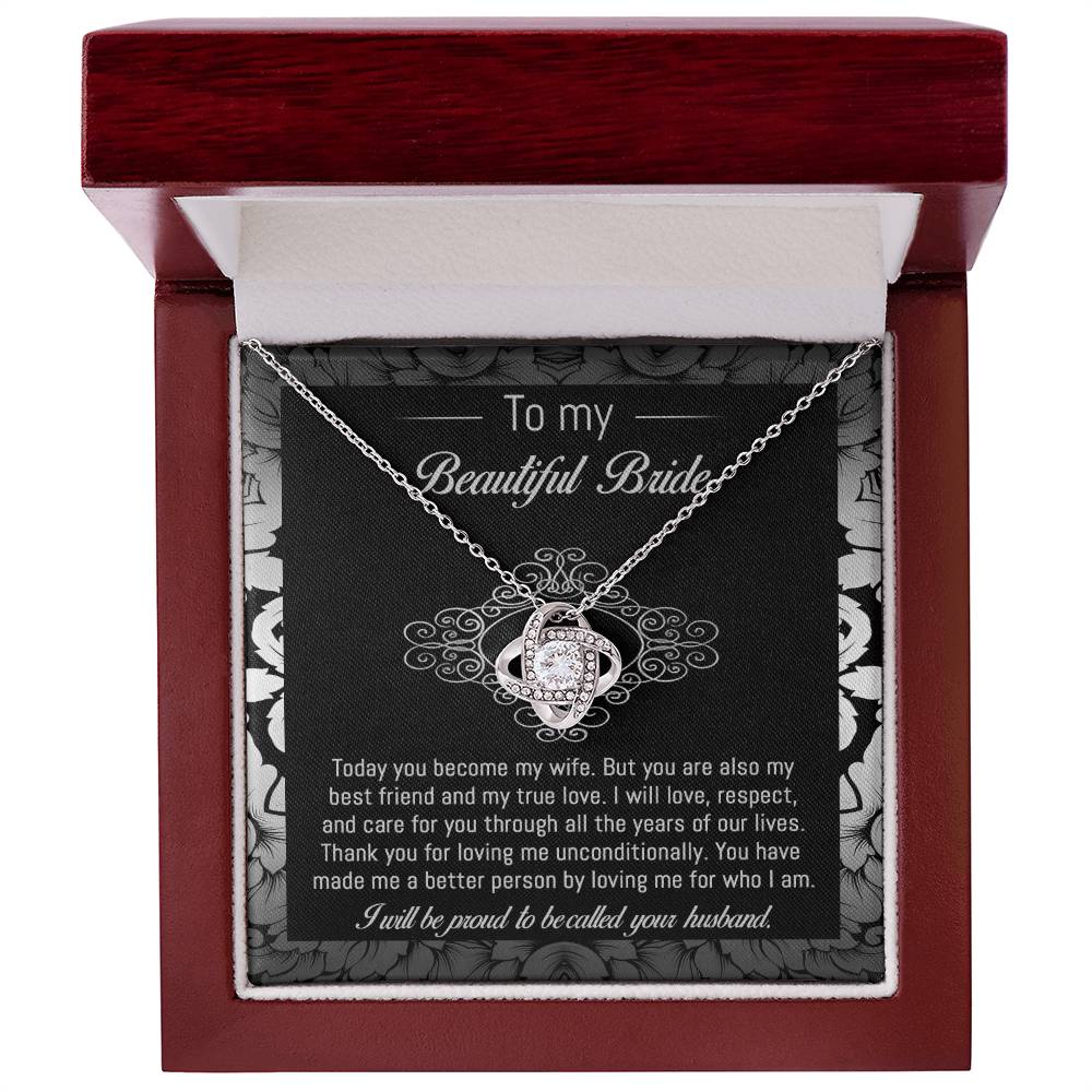 The "To Bride, My True Love - Love Knot Necklace" with a diamond pendant is displayed in a black and white box adorned with a floral pattern. The box, featuring cubic zirconia crystals, includes a heartfelt message addressed to "my beautiful bride" from her husband.