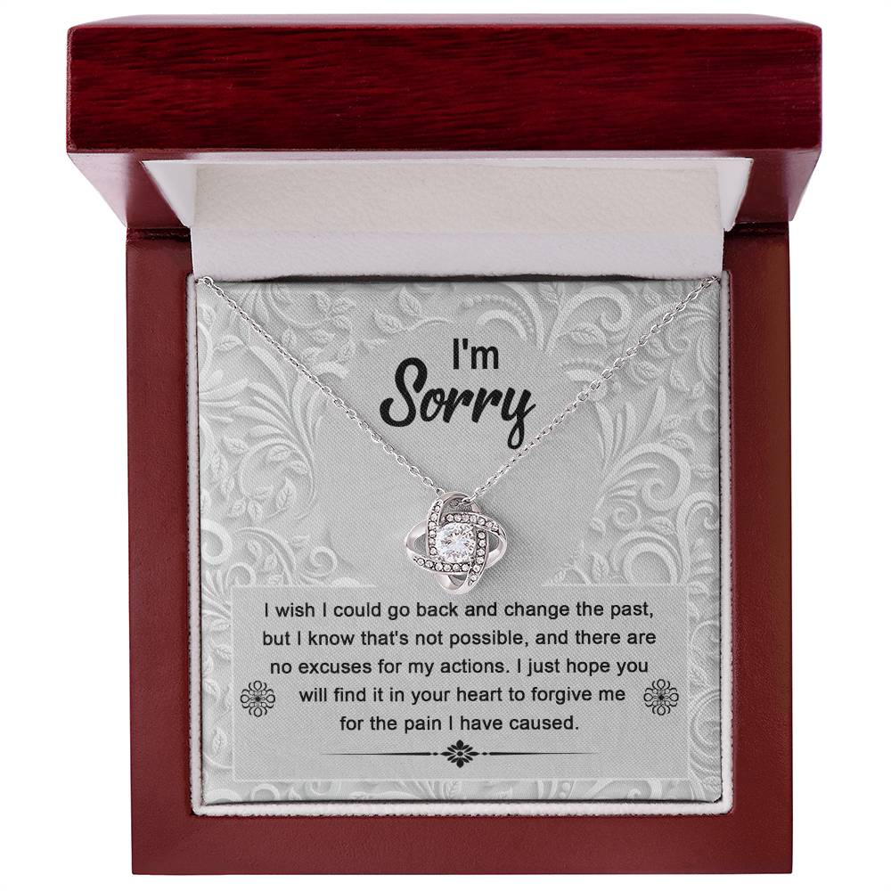 The Sorry-Change The Past - Love Knot Necklace with a white gold finish sits in a box with an apology message that reads, "I'm Sorry. I wish I could go back and change the past... I just hope you will find it in your heart to forgive me." The pendant sparkles with cubic zirconia crystals, symbolizing the unbreakable bond of love.