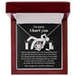 The Sorry-Change The Past 2 - Love Knot Necklace, featuring a pendant adorned with cubic zirconia crystals, is gracefully showcased on black fabric. It includes an apology message addressing past hurt and a heartfelt plea for forgiveness, complemented by illustrations of a distressed figure.
