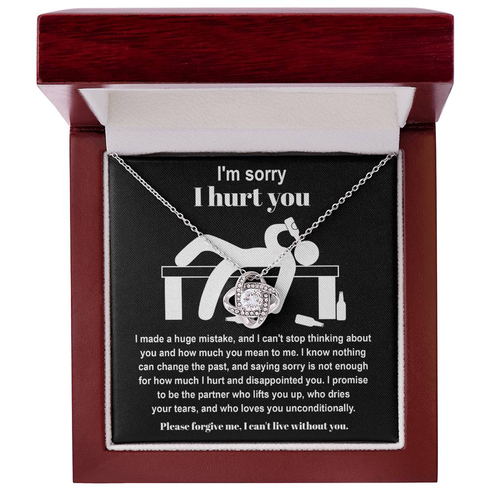 The Sorry-Change The Past 2 - Love Knot Necklace, featuring a pendant adorned with cubic zirconia crystals, is gracefully showcased on black fabric. It includes an apology message addressing past hurt and a heartfelt plea for forgiveness, complemented by illustrations of a distressed figure.