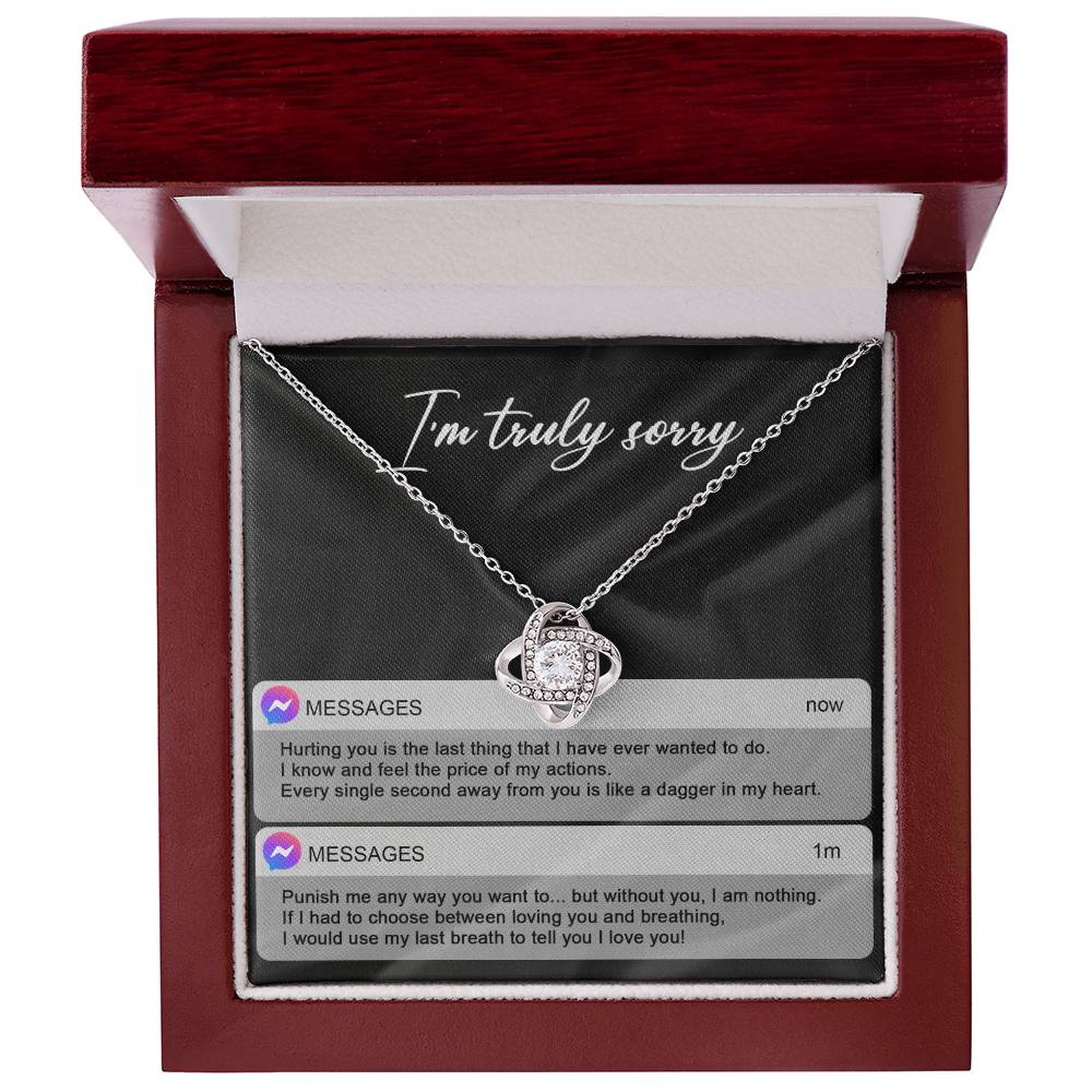 The Sorry-Away From You - Love Knot Necklace features interwoven heart pendants adorned with cubic zirconia crystals, and comes in a box with "I'm truly sorry" inscribed above. Accompanying the necklace are two text message excerpts expressing regret and love, making it an ideal personalized gift.