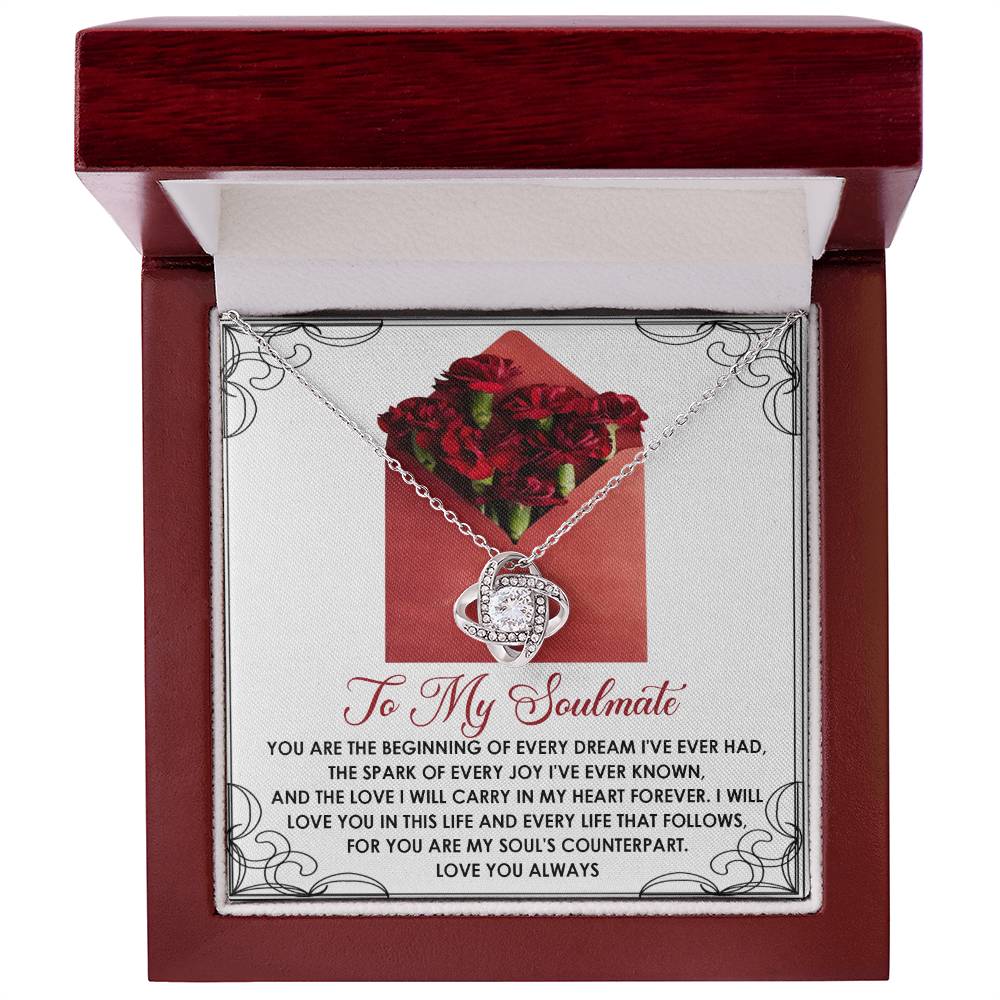 The Soulmate-My Heart Forever Love Knot Necklace comes in a box with a romantic message, showcasing a silver pendant adorned with cubic zirconia crystals, surrounded by red roses.