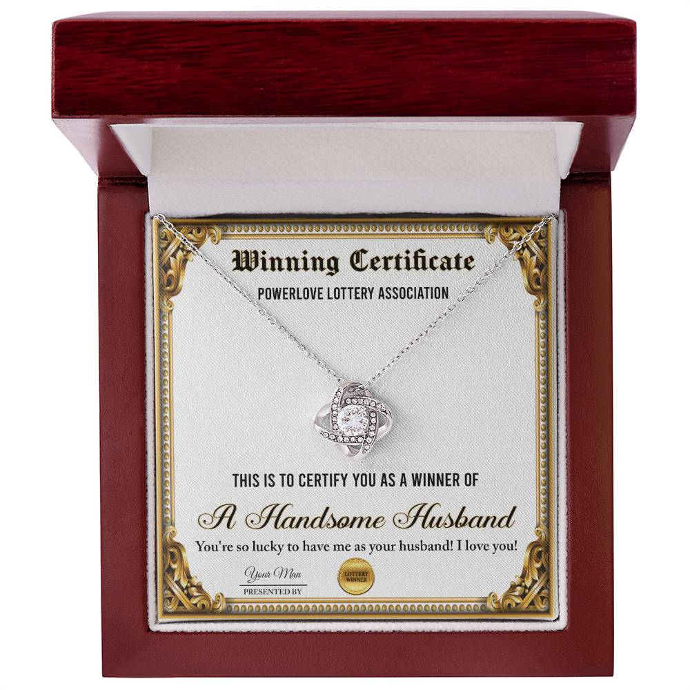 A "To Wife, Winning Certificate - Love Knot Necklace" is displayed against a certificate text background reading, "Winning Certificate - Powerlove Lottery Association - A Handsome Husband," featuring shimmering cubic zirconia crystals and an elegant gold finish.